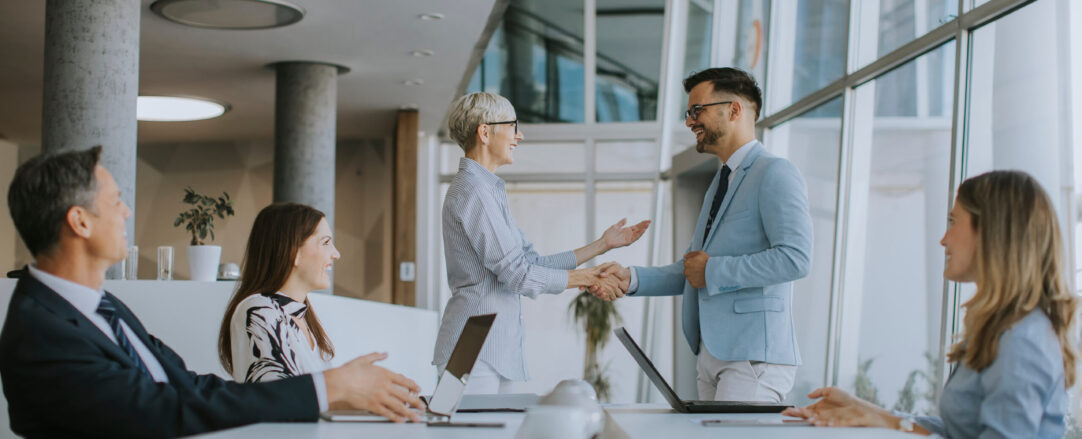 Mature business woman handshaking with young colleague on a meet Mature business woman handshaking with young colleague on a meet